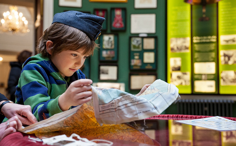 School student exploring a map, wearing a RAF cap from the Museum's handling collection
